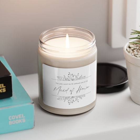 A picture of our 9 Oz Soy Candle with the label that says The Aisle wont be lit without you as my Maid of Honor. There are Beautiful floral border drawing on the top and bottom of the saying, in simple and elegant black ink color.