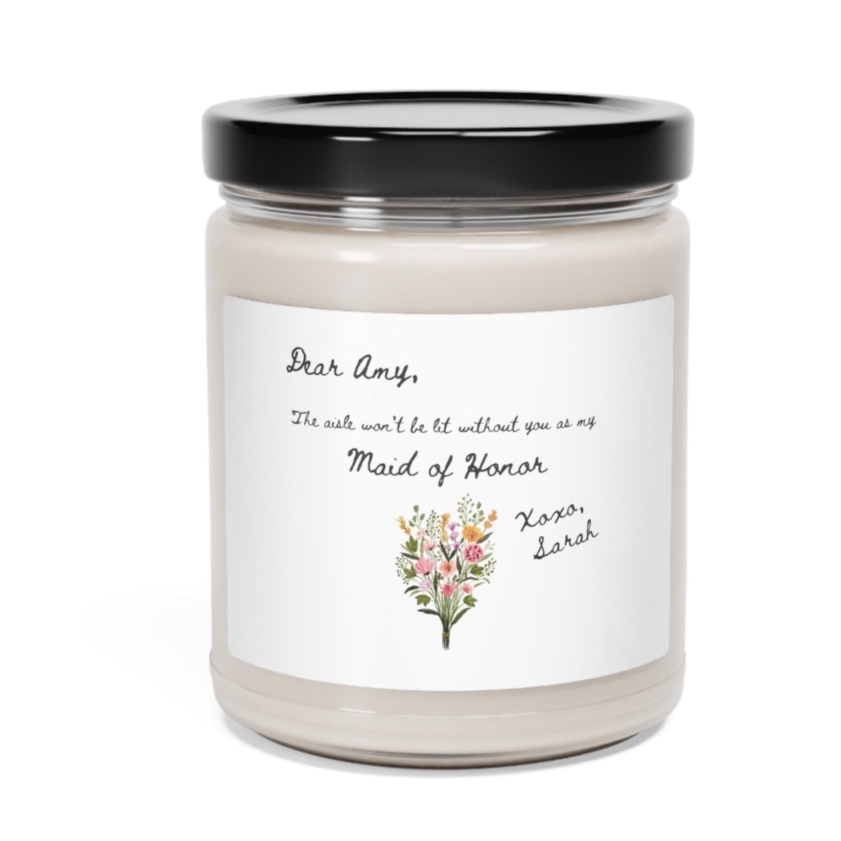 A picture of our 9 Oz Soy Candle with the label that says Dear Amy, The Aisle wont be lit without you as my Maid of Honor. Xoxo, Sarah. The names can be personalized. It is also adorned with an image of a beautiful bouquet of flowers.