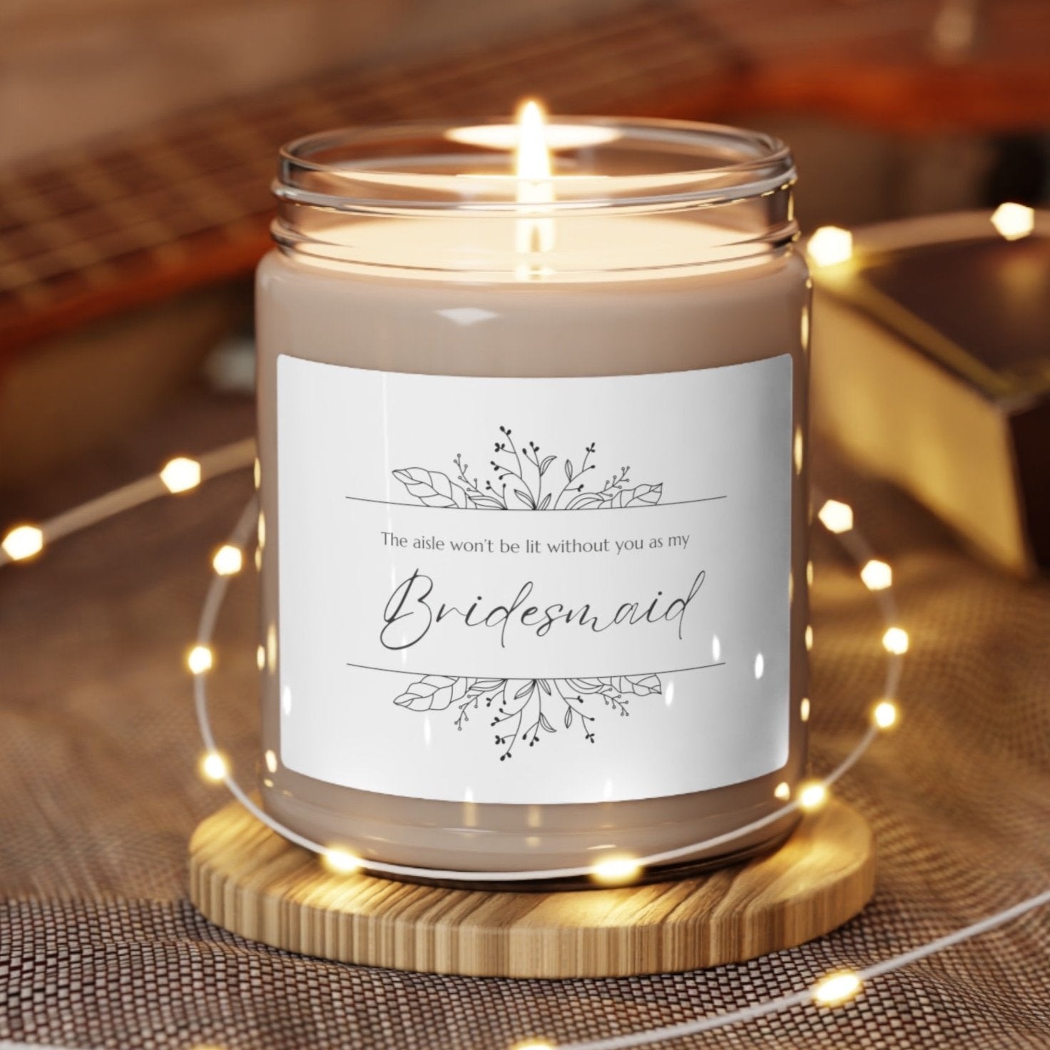 A picture of our 9 Oz Soy Candle with the label that says The Aisle wont be lit without you as my Bridesmaid. There are Beautiful floral border drawing on the top and bottom of the saying, in simple and elegant black ink color.