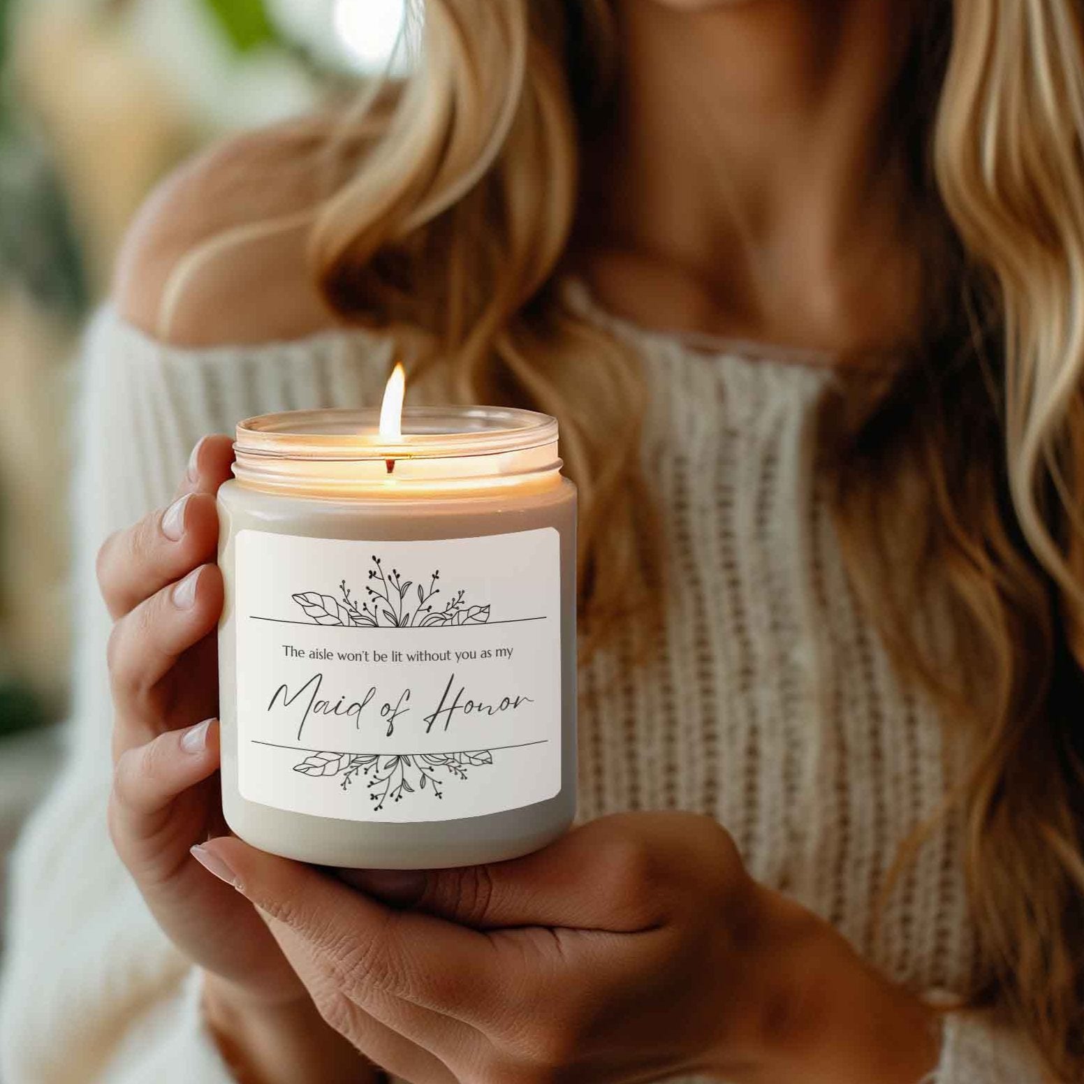 A picture of our 9 Oz Soy Candle with the label that says The Aisle wont be lit without you as my Maid of Honor. There are Beautiful floral border drawing on the top and bottom of the saying, in simple and elegant black ink color.