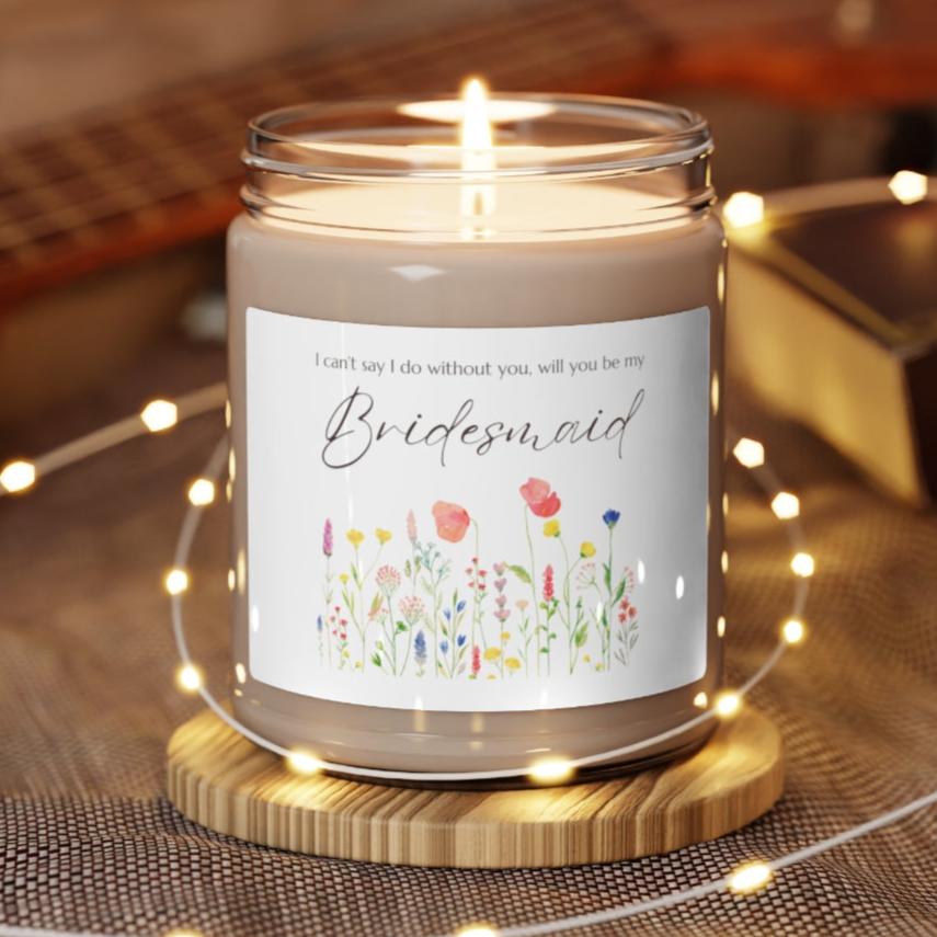 A picture of a glass jar of our lit soy candle that says: I cant say I do without you, will you be my Bridesmaid. There is a lovely painted style wild flower graphic underneath the sayings.